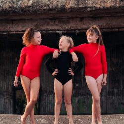 two dancers in red leotards, one in black